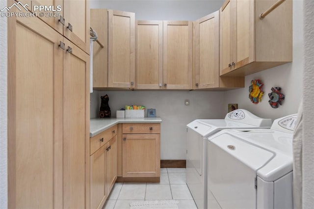 clothes washing area featuring light tile patterned flooring, cabinets, and washer and dryer