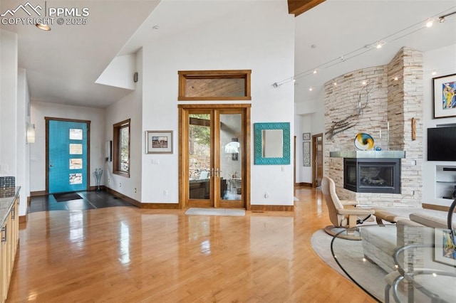 living room with a towering ceiling, a fireplace, track lighting, and hardwood / wood-style floors