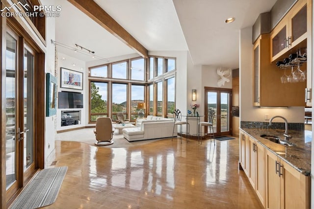 interior space featuring a towering ceiling, plenty of natural light, sink, and french doors