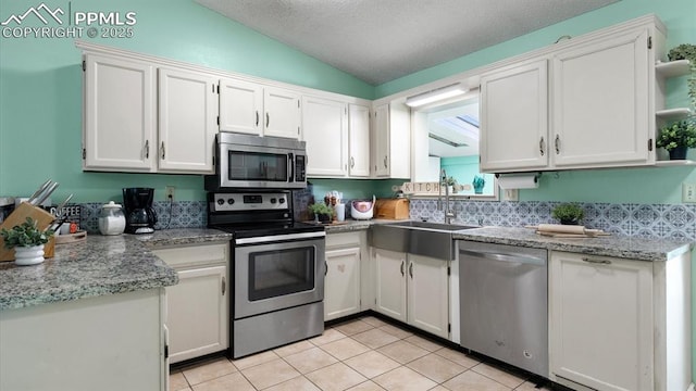 kitchen featuring lofted ceiling, sink, stainless steel appliances, and white cabinets