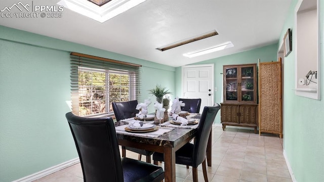 tiled dining space with vaulted ceiling with skylight