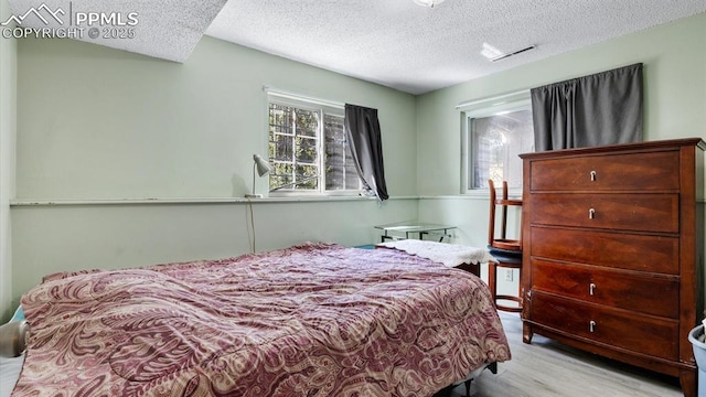 bedroom featuring light hardwood / wood-style flooring and a textured ceiling