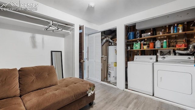 laundry room with washing machine and clothes dryer, water heater, and light hardwood / wood-style flooring