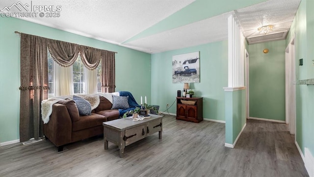 living room featuring hardwood / wood-style flooring, vaulted ceiling, and a textured ceiling