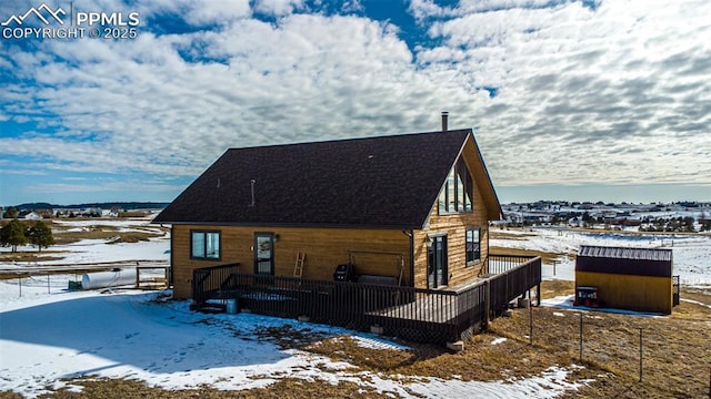 view of snow covered exterior with a wooden deck and a storage shed