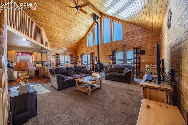 carpeted living room featuring wood walls, wood ceiling, high vaulted ceiling, a wood stove, and ceiling fan