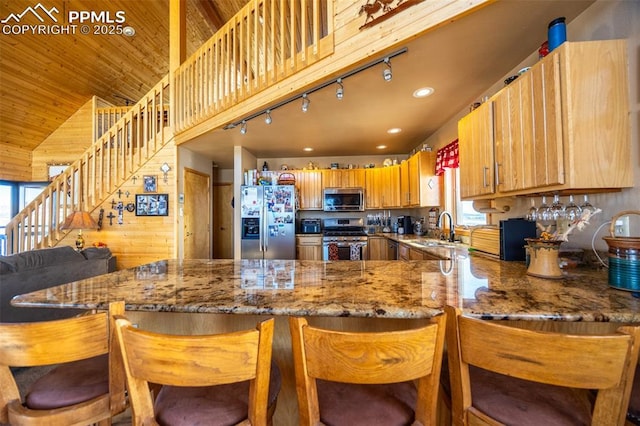 kitchen with a kitchen bar, sink, wood ceiling, kitchen peninsula, and stainless steel appliances