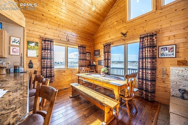 dining space with a water view, a wealth of natural light, and wood walls