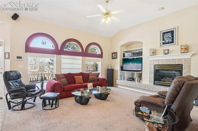 living room with ceiling fan, lofted ceiling, a tiled fireplace, and carpet floors