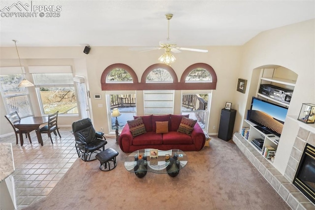 carpeted living room with ceiling fan, lofted ceiling, and a tile fireplace