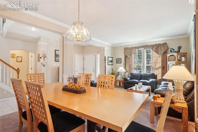 dining space featuring tile patterned flooring, ornamental molding, and an inviting chandelier