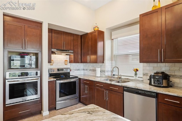 kitchen featuring tasteful backsplash, sink, light tile patterned floors, light stone counters, and stainless steel appliances