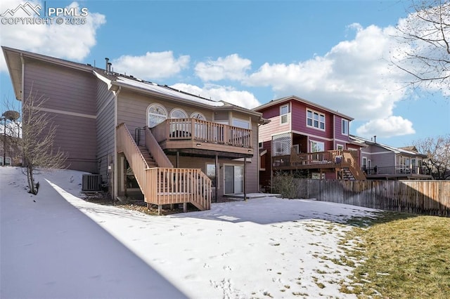 snow covered property with central AC and a deck