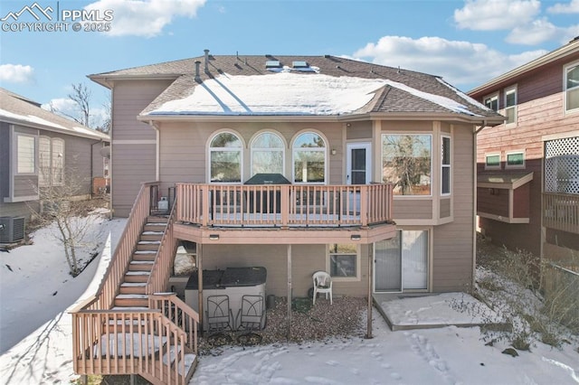 snow covered property featuring cooling unit, a wooden deck, and a jacuzzi