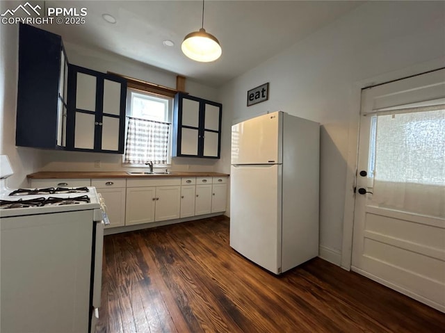 kitchen with dark wood-type flooring, sink, pendant lighting, white appliances, and white cabinets