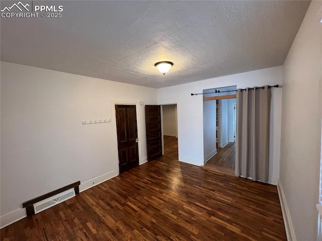 unfurnished room with dark hardwood / wood-style floors, a barn door, and a textured ceiling