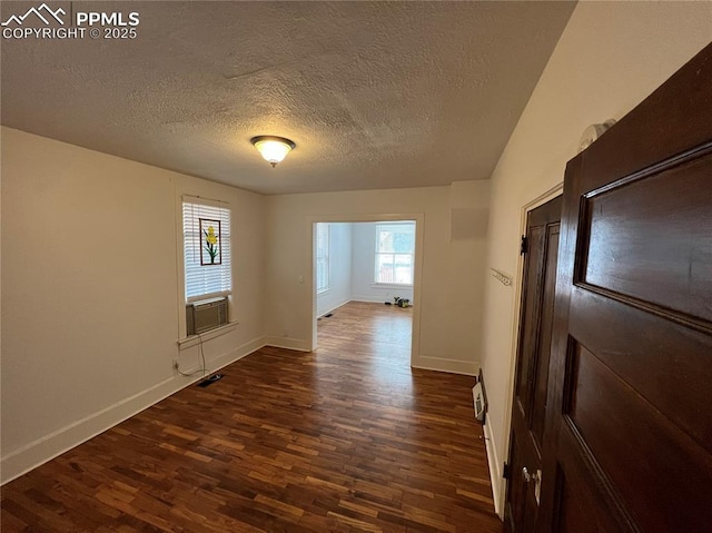 unfurnished room featuring dark wood-type flooring and a textured ceiling