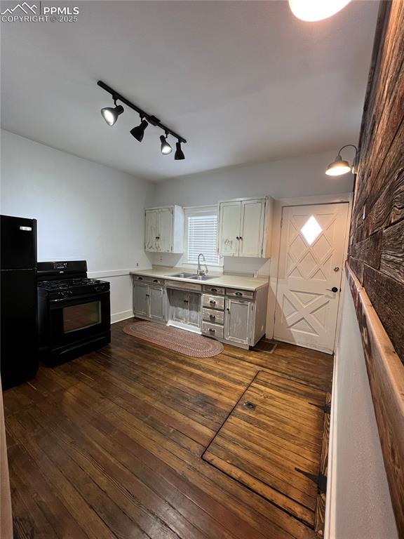 kitchen with sink, rail lighting, white cabinetry, dark hardwood / wood-style floors, and black appliances