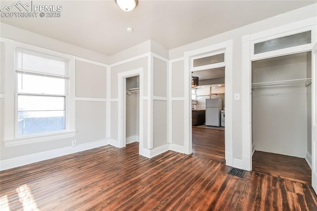 unfurnished bedroom featuring dark hardwood / wood-style flooring and white fridge