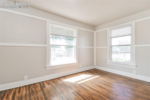 empty room with plenty of natural light and hardwood / wood-style floors