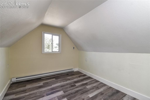 additional living space with dark wood-type flooring, lofted ceiling, a textured ceiling, and a baseboard heating unit