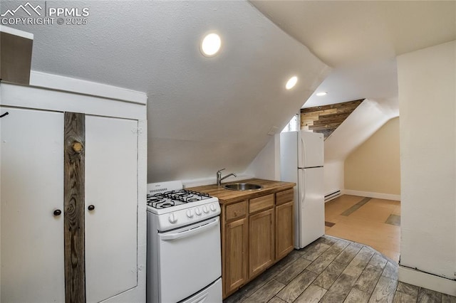 kitchen with lofted ceiling, sink, white appliances, and a baseboard heating unit