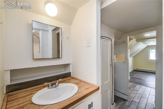 bathroom with vanity, a baseboard radiator, and lofted ceiling