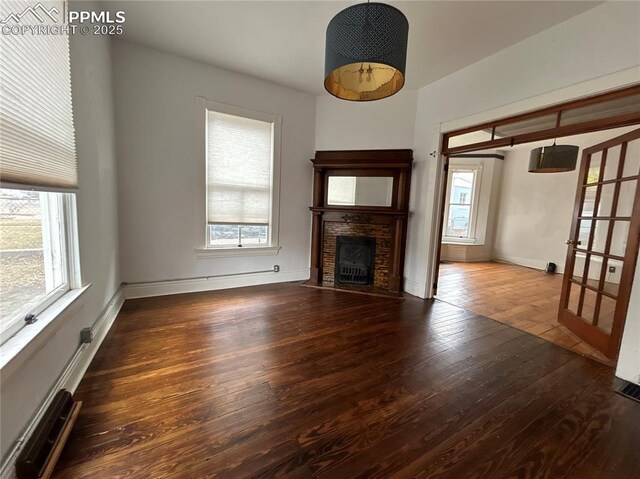 unfurnished living room with french doors, dark hardwood / wood-style flooring, and a brick fireplace