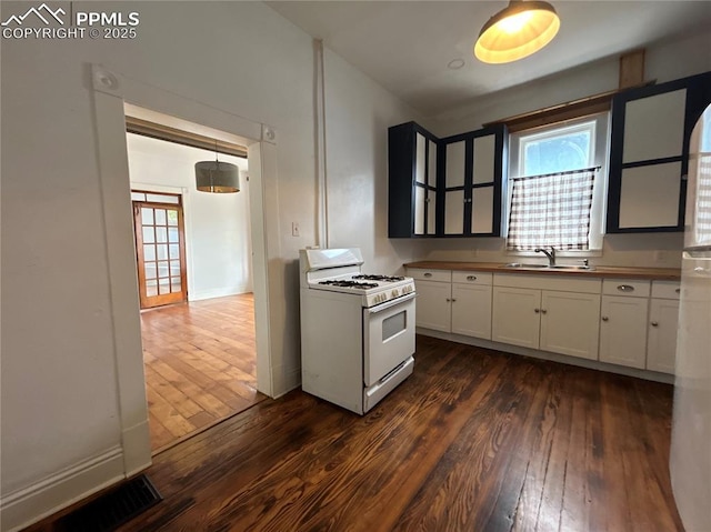 kitchen featuring sink, white cabinetry, dark hardwood / wood-style flooring, white appliances, and a healthy amount of sunlight