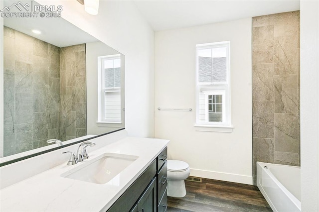 full bathroom with wood-type flooring, tiled shower / bath, vanity, and toilet