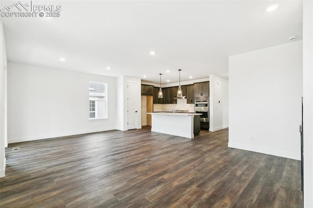 unfurnished living room featuring dark wood-type flooring and sink