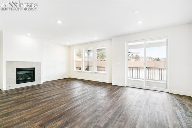 unfurnished living room with a tile fireplace and dark hardwood / wood-style flooring