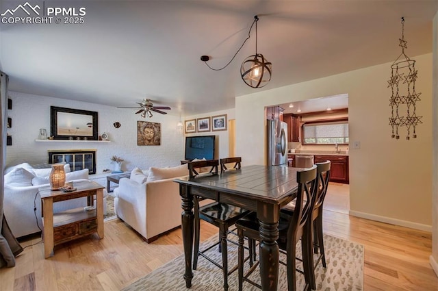 dining space featuring ceiling fan, sink, and light wood-type flooring