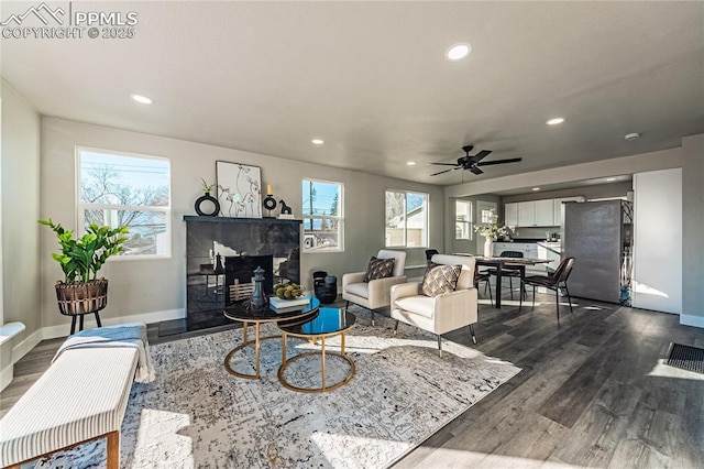 living room featuring dark hardwood / wood-style floors, ceiling fan, and a fireplace