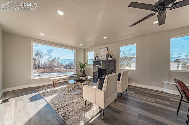 living room featuring a premium fireplace, ceiling fan, and dark hardwood / wood-style flooring