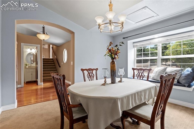 dining area with light carpet, a notable chandelier, and sink