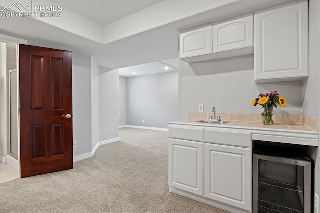 kitchen with white cabinetry, sink, light carpet, and wine cooler