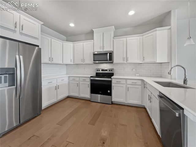 kitchen with stainless steel appliances, decorative light fixtures, sink, and white cabinets