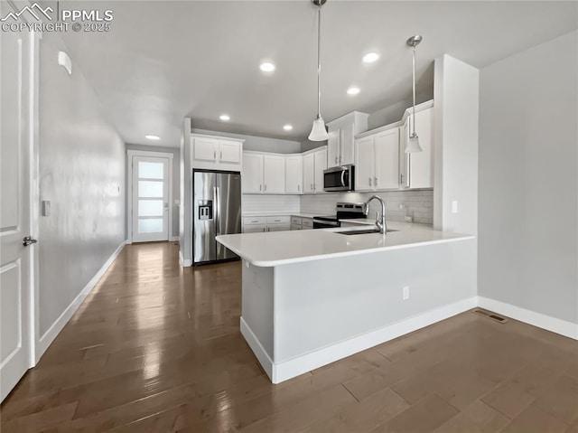 kitchen with pendant lighting, white cabinetry, sink, kitchen peninsula, and stainless steel appliances