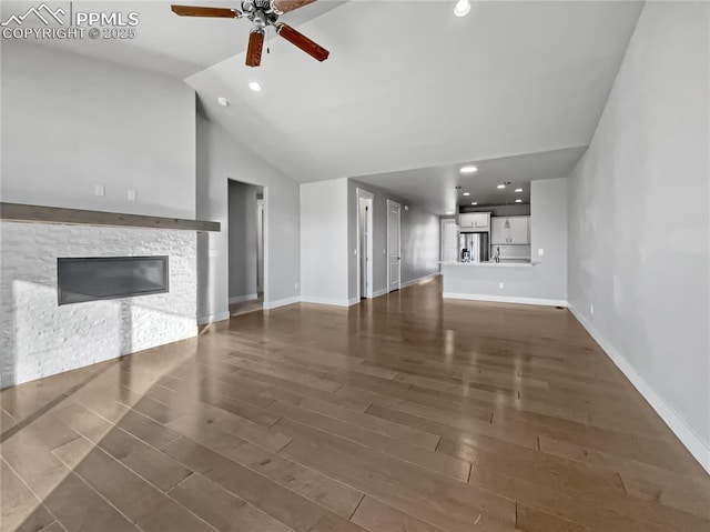 unfurnished living room featuring dark hardwood / wood-style floors, ceiling fan, a fireplace, and high vaulted ceiling