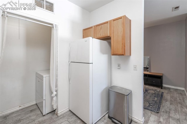 kitchen with white refrigerator, washer / clothes dryer, light hardwood / wood-style floors, and light brown cabinets