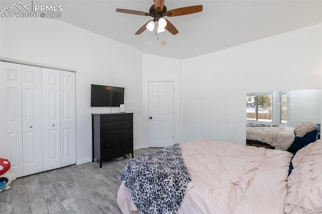 bedroom featuring ceiling fan, vaulted ceiling, a closet, and light wood-type flooring