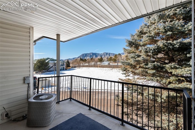 snow covered back of property featuring a mountain view and central air condition unit