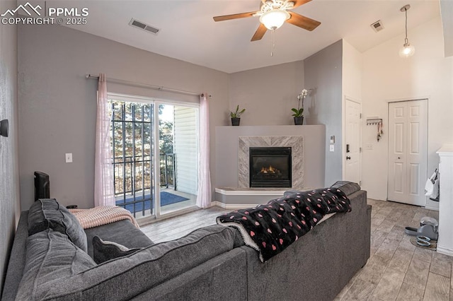 living room featuring lofted ceiling, a fireplace, and ceiling fan