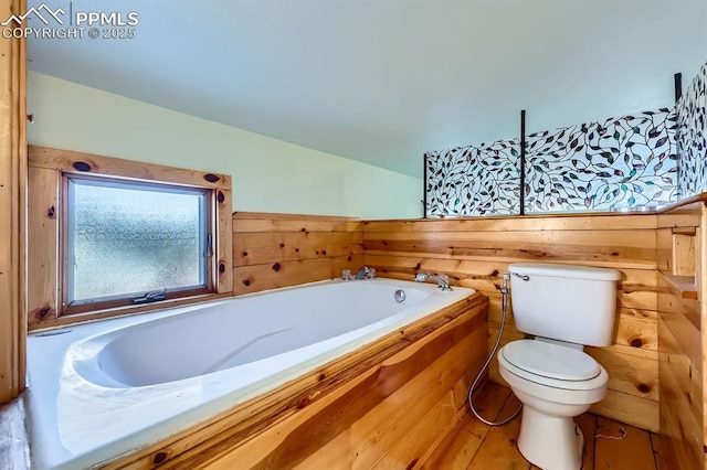 bathroom featuring a tub to relax in, vaulted ceiling, wooden walls, and toilet