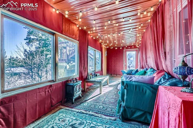 sunroom / solarium featuring wood ceiling and a wood stove