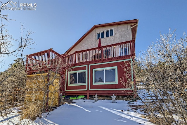 snow covered back of property with a wooden deck