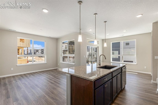 kitchen featuring a sink, baseboards, open floor plan, dark wood-style floors, and pendant lighting