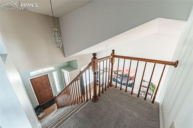 stairway featuring a towering ceiling, carpet flooring, and a textured ceiling