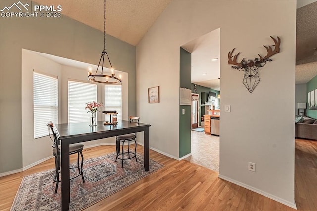 dining room featuring high vaulted ceiling, a chandelier, hardwood / wood-style floors, and a textured ceiling